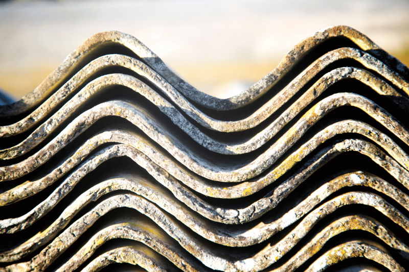 Pile of asbestos cement sheeting, neatly stacked on top of one another.