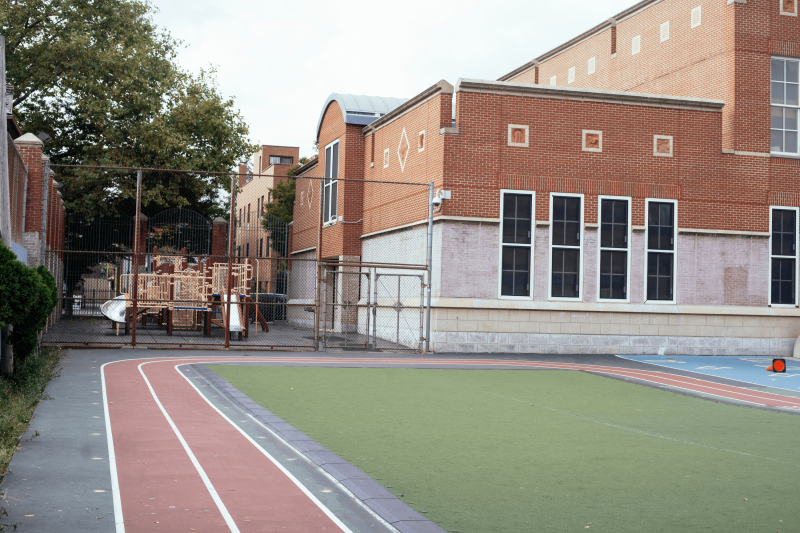 School building, athletics area and fenced off playground.