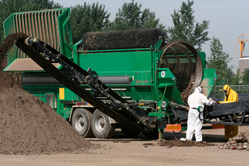 Two asbestos removalists sorting through asbestos contaminated soil.